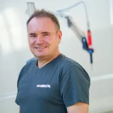 Jürg Schlechten, Servicetechniker bei CREAMETAL, vor einem an einem Gelenkarm hängenden Werkstattgerät