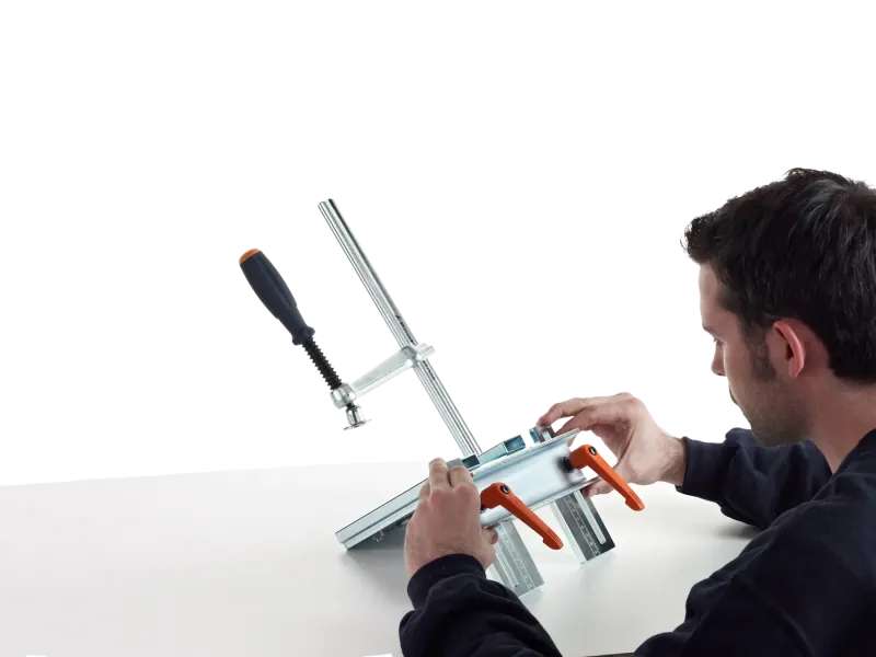 Metallbauer stellt die CREA-HEAVY am Arbeitstisch ein und löst dazu die beiden orangen Klemmhebel